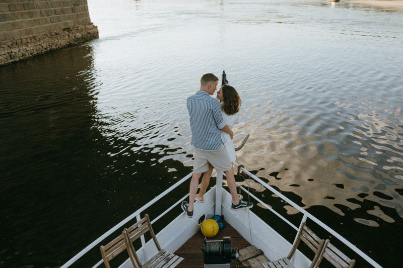 Couple standing at the bow of a yacht at sunset