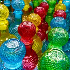 Rows of coloured cut-glass bottles catching the light, photo by Alex on Pexels
