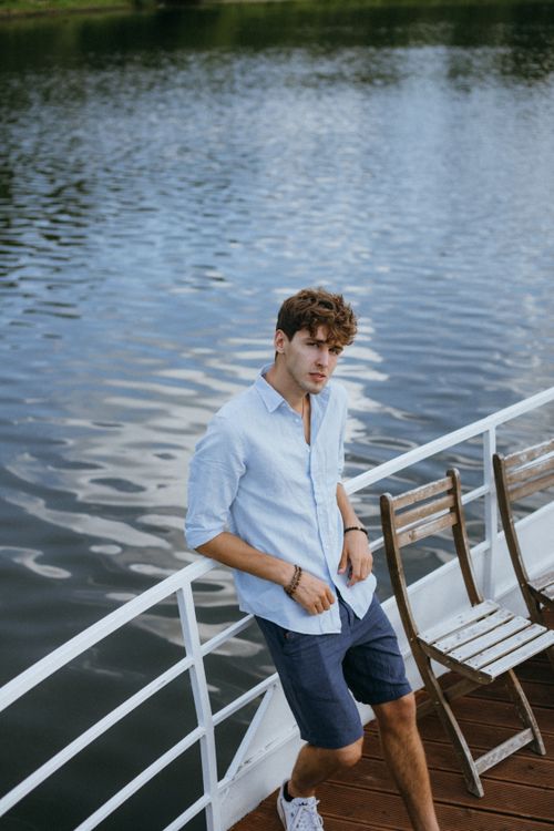 Free Stylish young man leaning on a boat railing by the tranquil river. Stock Photo