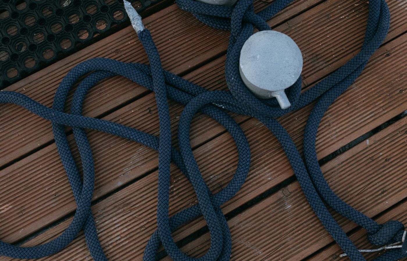 Close-up of a nautical rope coiled on a wooden dock with bollards, emphasizing texture.