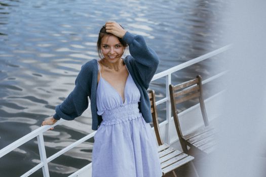 Woman in Blue Knitted Cardigan and Blue Dress Standing near the Taffrail