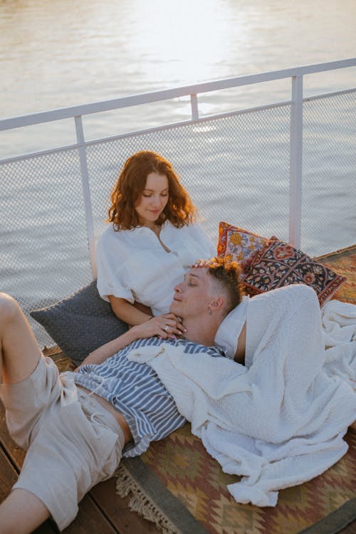 {{https://mixerdates.com/?ch=mixerblog}} Couple enjoying a relaxing sunset moment on a yacht's deck, surrounded by pillows
