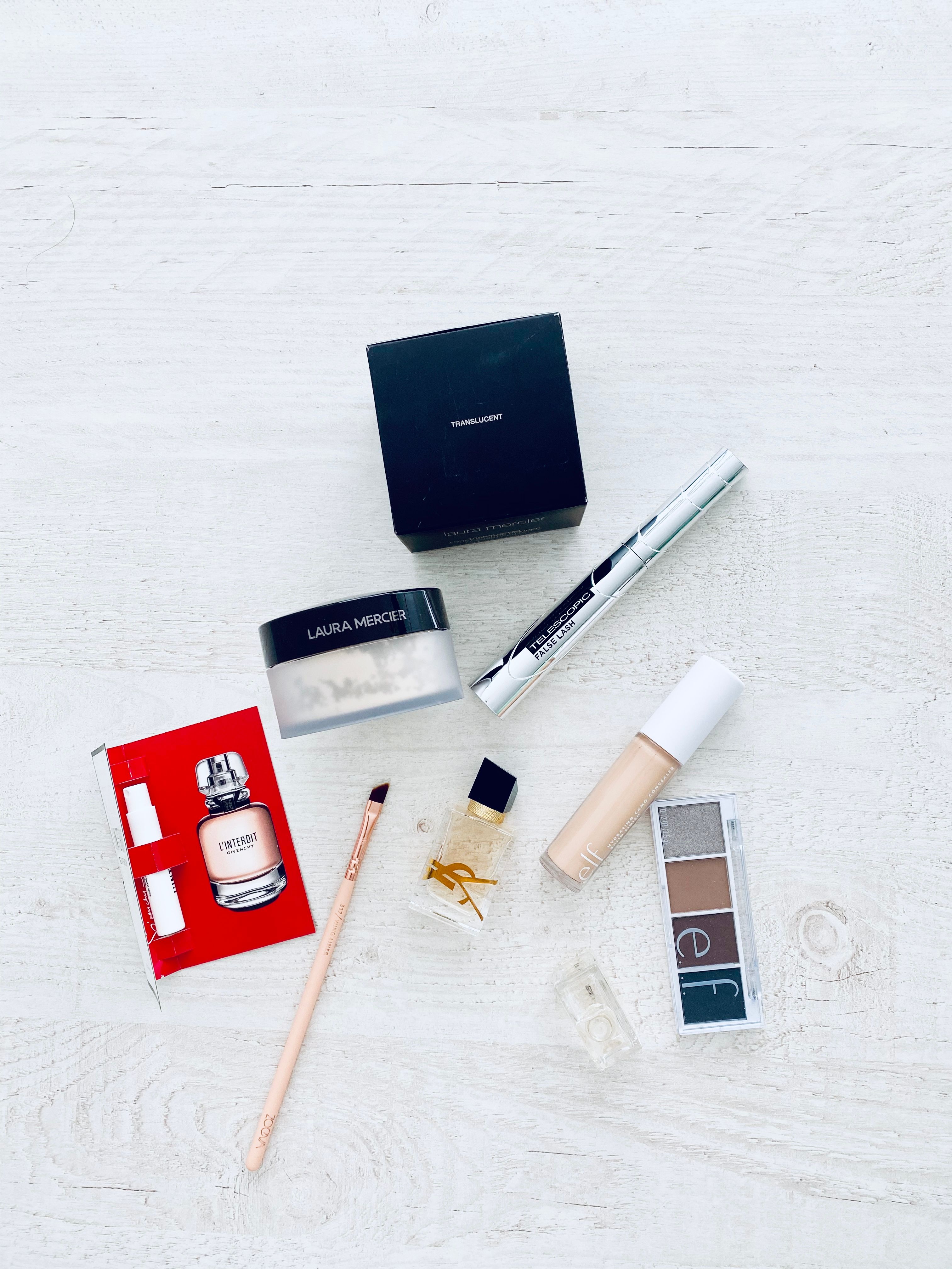 A stylish collection of luxury makeup items displayed on a white background, perfect for beauty enthusiasts.