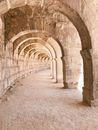 Old shabby stone construction with arched empty passage and sandy ground on street on sunny summer day
