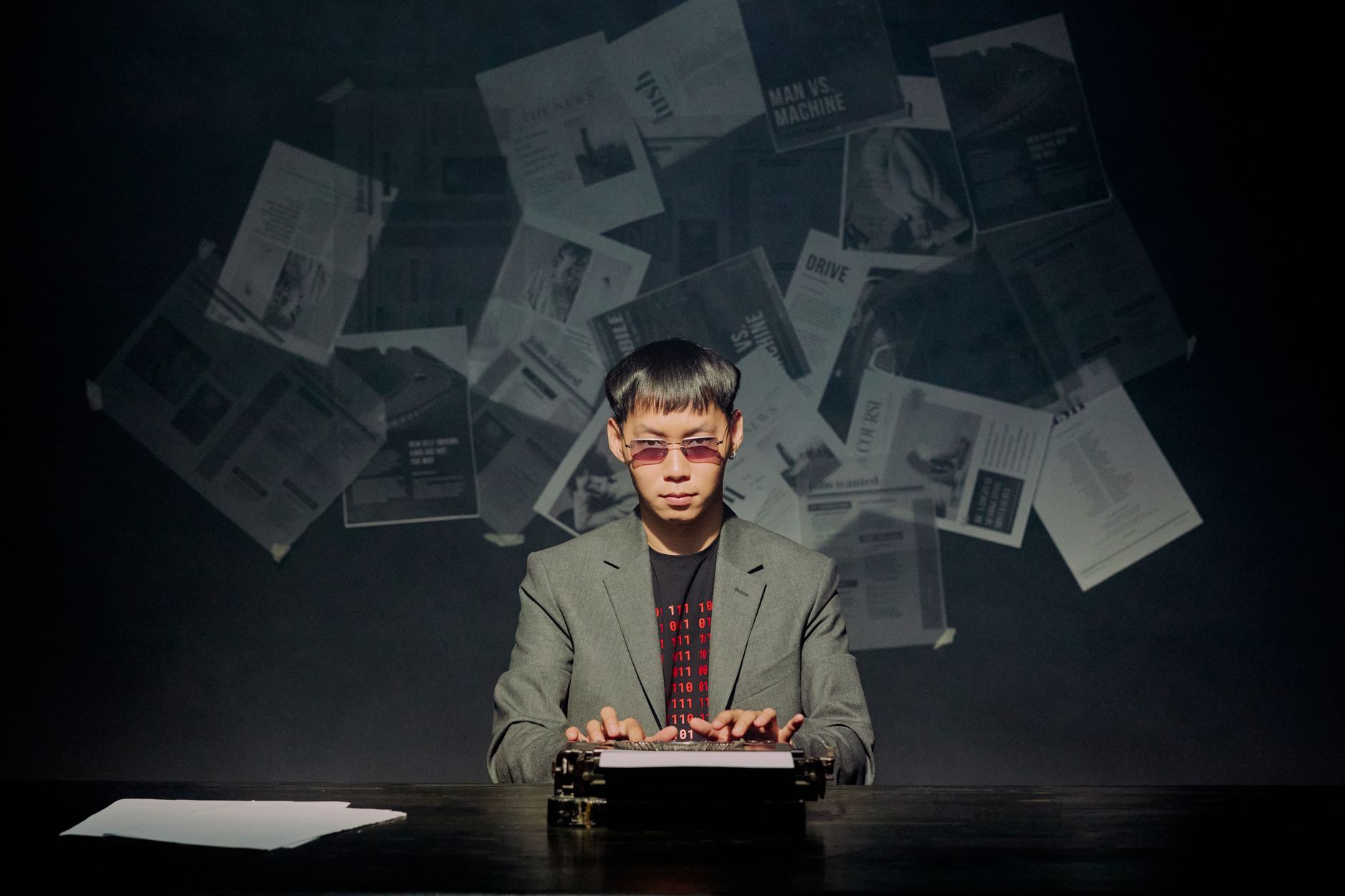 Man in a suit typing on a vintage typewriter with papers floating in the background.