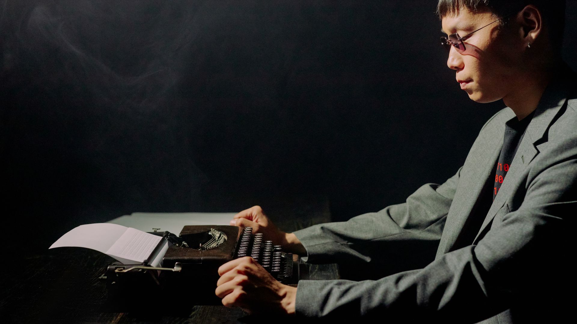 Modafinil for Freelance Writers: Boosting Productivity and Creativity 3 A man in a suit types on a vintage typewriter in a dimly lit room, creating an atmospheric scene — modafinil for freelance writers