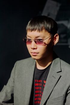 Portrait of a fashionable man wearing a gray suit and sunglasses indoors.