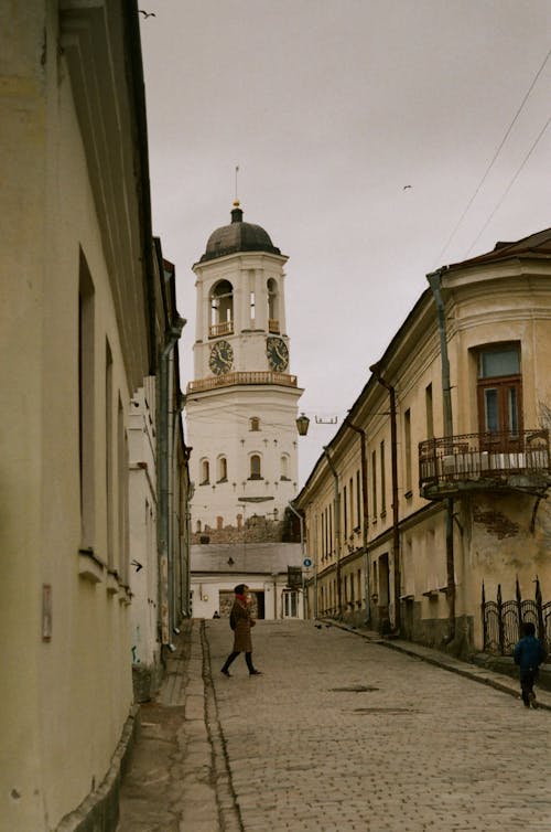 People on a Narrow Cobblestone Street with a Clock Tower, Vyborg