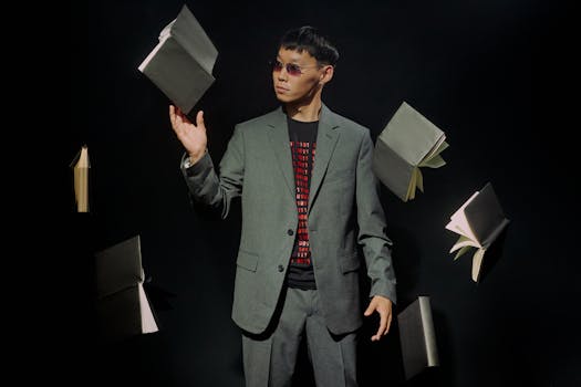 Asian man in gray suit and sunglasses with floating books, black background.