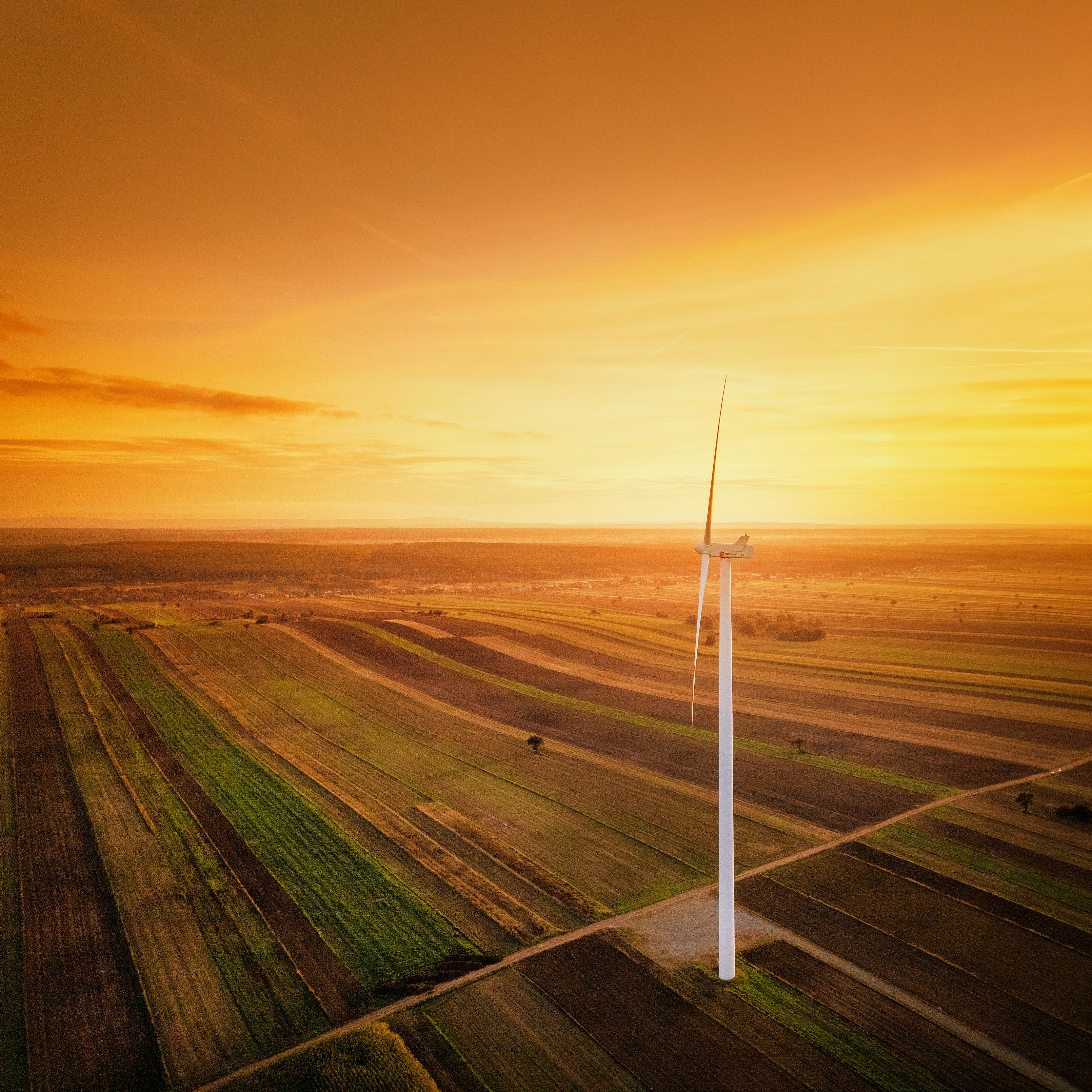 A picturesque aerial shot of a wind turbine in golden hour over the Polish countryside in Iłża.