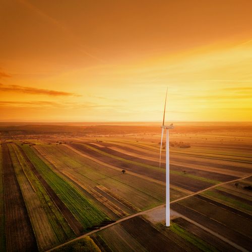 Free A picturesque aerial shot of a wind turbine in golden hour over the Polish countryside in Iłża. Stock Photo
