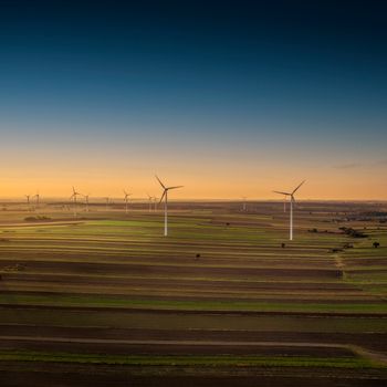 Aerial view of wind turbines in Iłża, Poland at sunset, showcasing sustainable energy in the countryside.