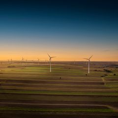 Wind turbines over farmland at sunset — photo by Piotr Arnoldes on Pexels
