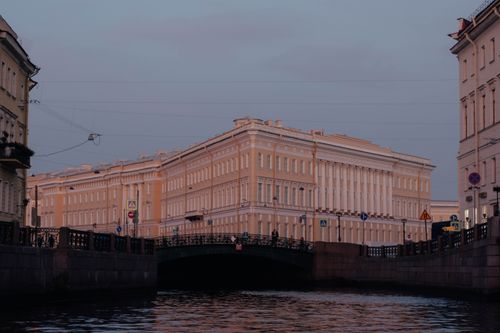 Free Elegant 19th-century buildings and bridges line a tranquil canal in Saint Petersburg, Russia, at dusk. Stock Photo