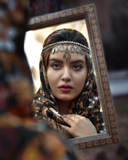 Free Elegant reflection of a woman in a mirror wearing a headscarf and jewelry, showcasing cultural fashion. Stock Photo