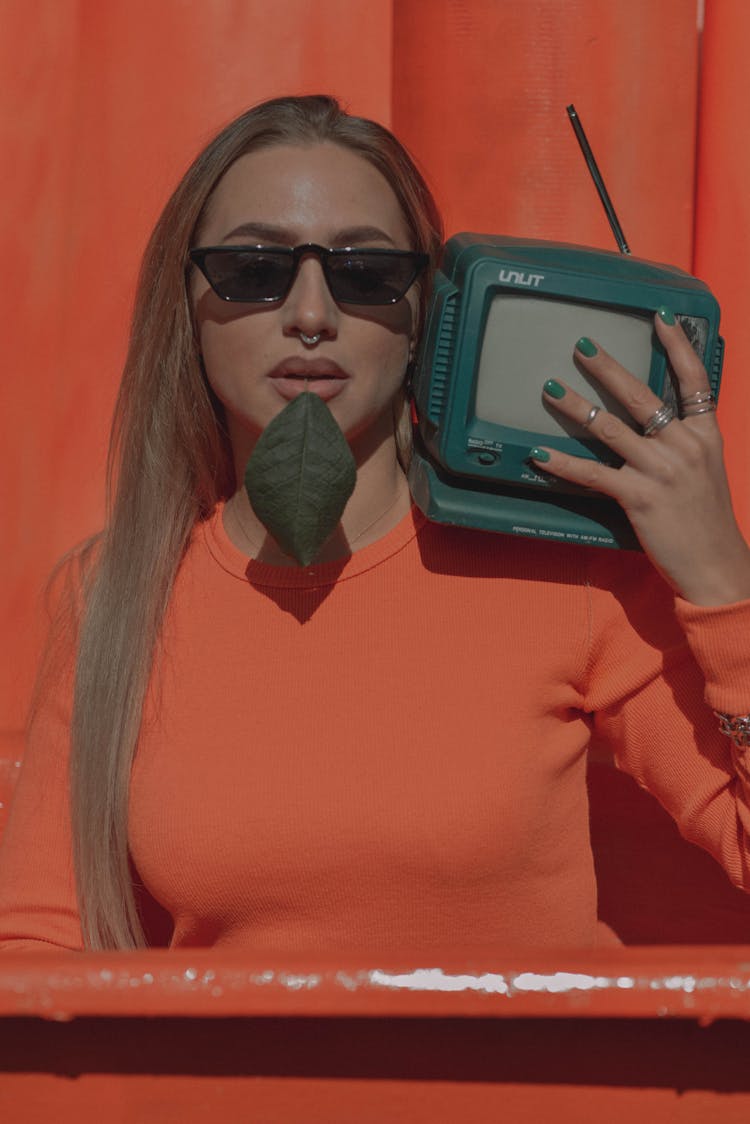 Woman Posing With Retro TV On Orange Background