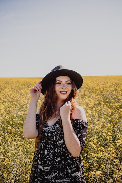 Free Woman Wearing a Sun Hat Standing on Flower Field Stock Photo