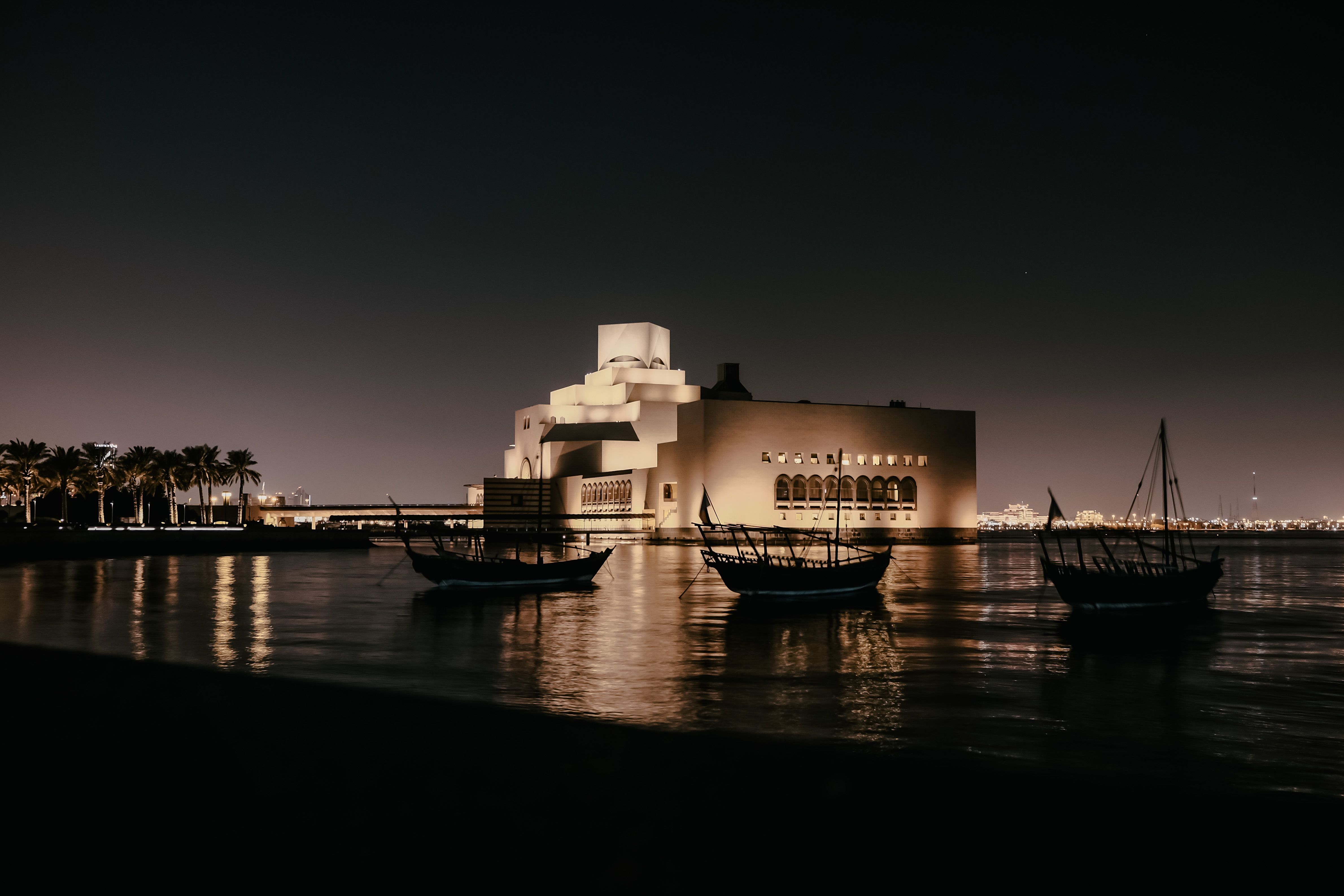 Stunning night view of an illuminated museum with boats in the foreground, reflecting serenity.