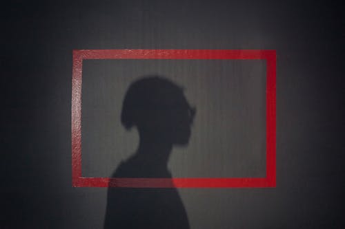 Shadow of mans profile on a black background with red square