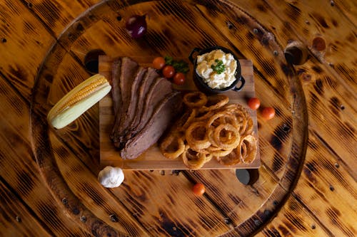 An Onion Rings and Steak on a Wooden Board