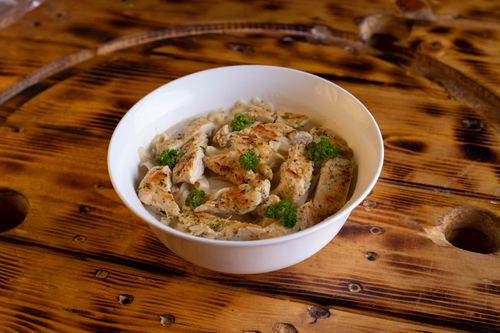 Free Tasty chicken pasta with herbs in a white bowl on rustic wooden table. Stock Photo