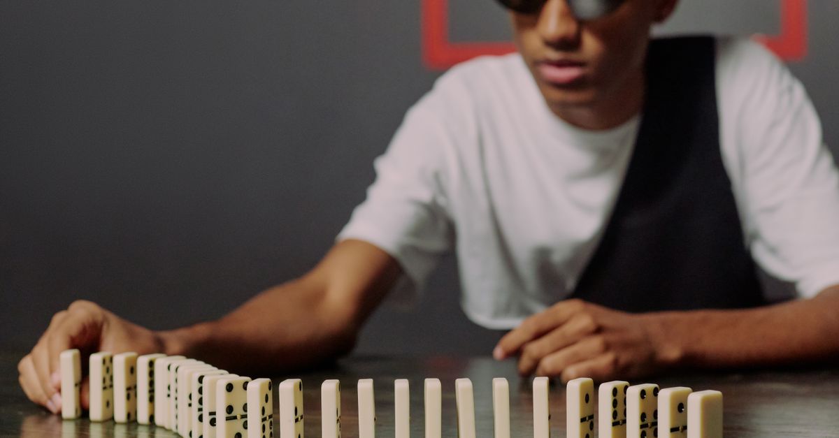 Dominic Blocks Man sitting and taking one of the domino blocks · Free Stock Photo