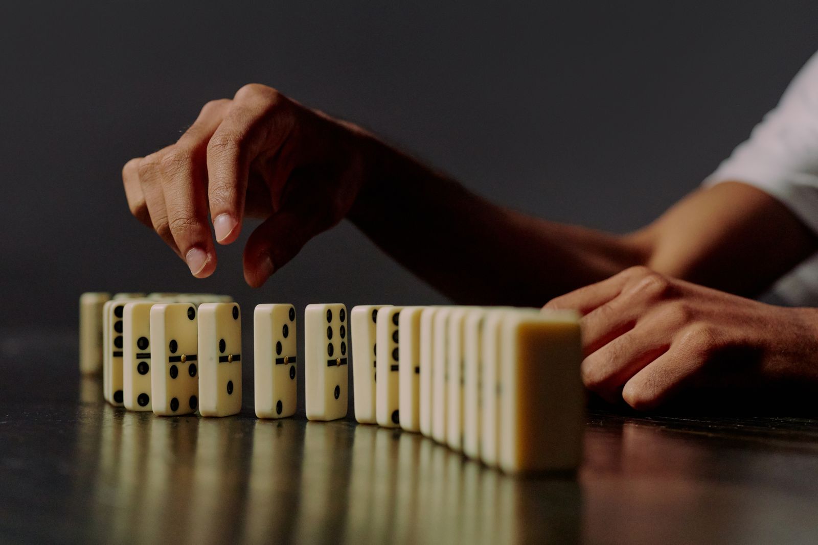 Hand lifting one domino out of an ordered row of matching dominoes