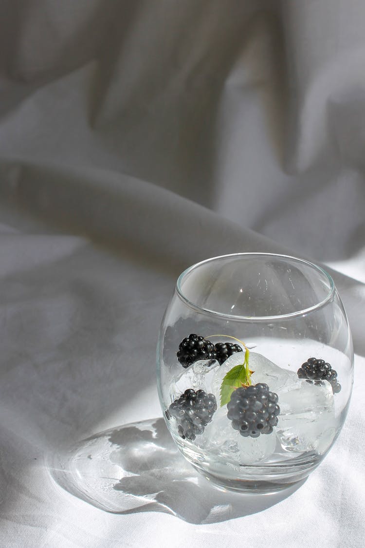 Glass With Ice Cubes And Blackberries On White Material