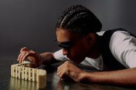 Man taking one of the domino blocks and focusing on it