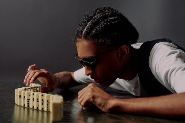 Man Taking One Of The Domino Blocks And Focusing On It