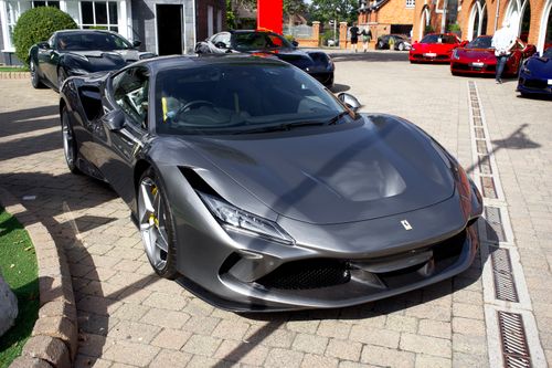 Free Elegant Ferrari sports car parked in a UK driveway, showcasing luxury design and vibrant color. Stock Photo