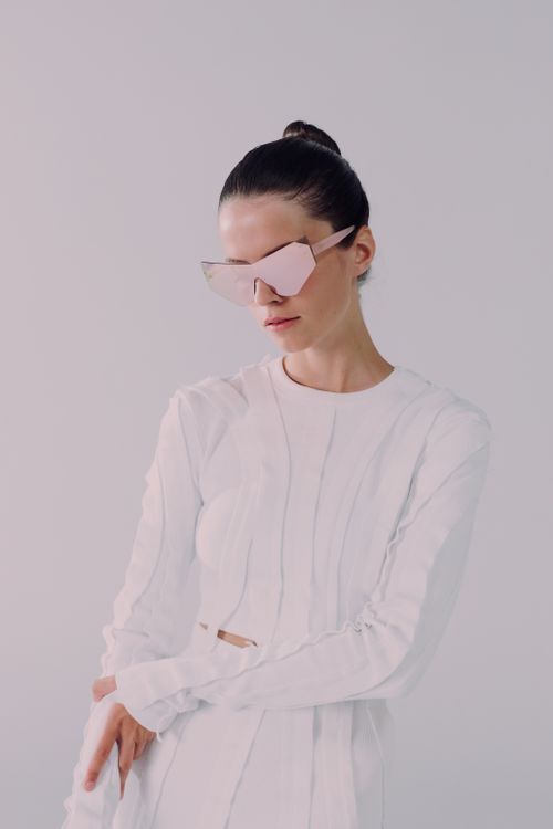 Free Elegant woman in white ensemble and unique sunglasses in a studio shot. Stock Photo