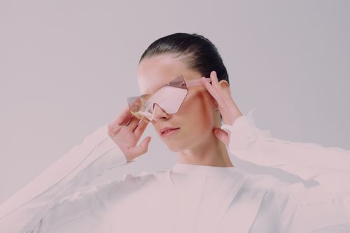 Free Stylish woman in futuristic glasses and white outfit in a minimalist studio setting. Stock Photo