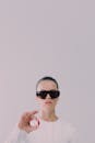 Studio shot of woman in sunglasses holding red pill