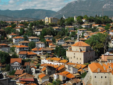 A picturesque aerial view of a traditional Ottoman village nestled in lush greenery under a clear sky.