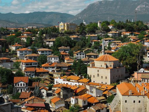 Free A picturesque aerial view of a traditional Ottoman village nestled in lush greenery under a clear sky. Stock Photo