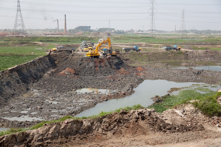 Trucks And Backhoe Working On Construction Site