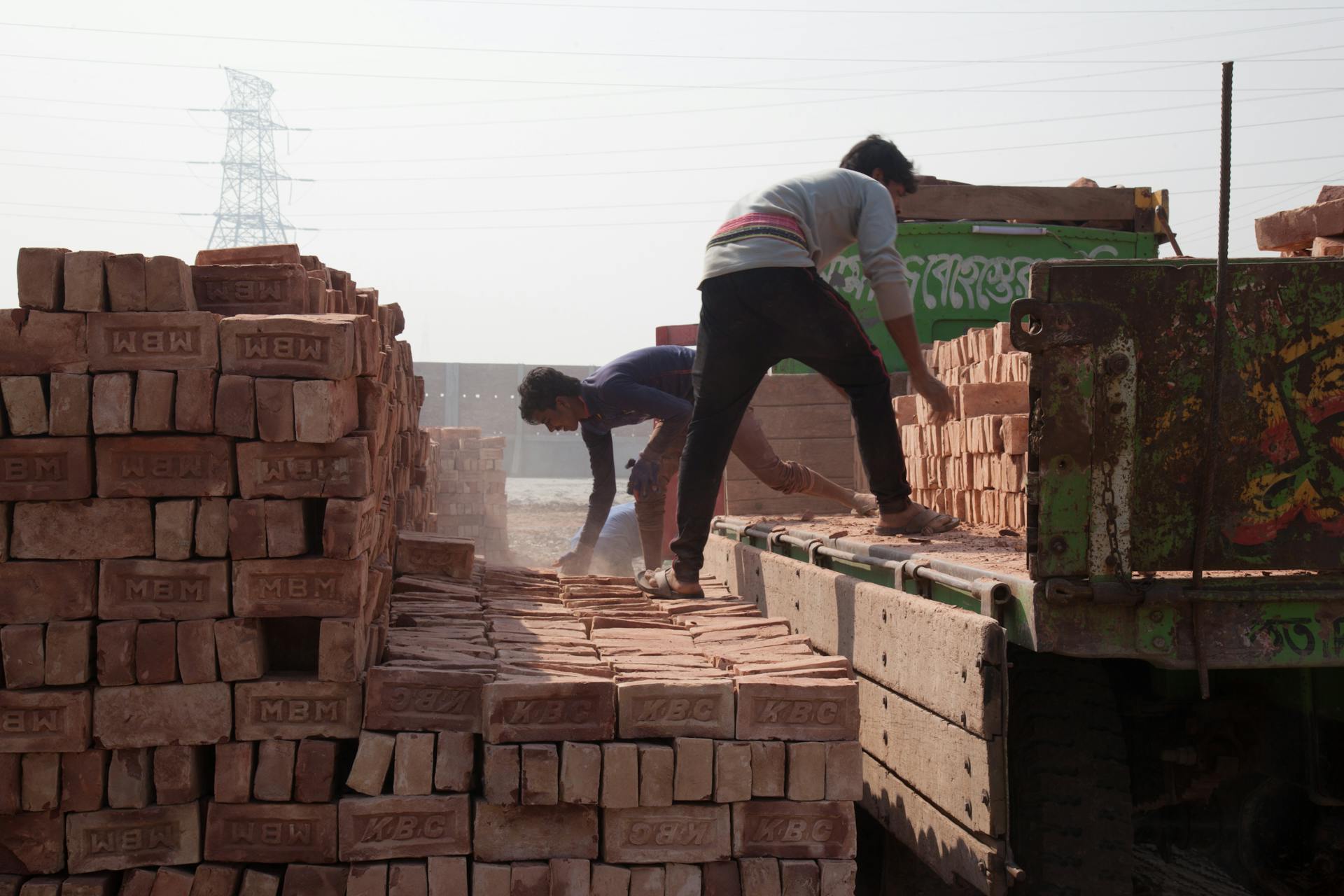 Men load bricks onto a truck at a construction site in Gabtoli, Dhaka.