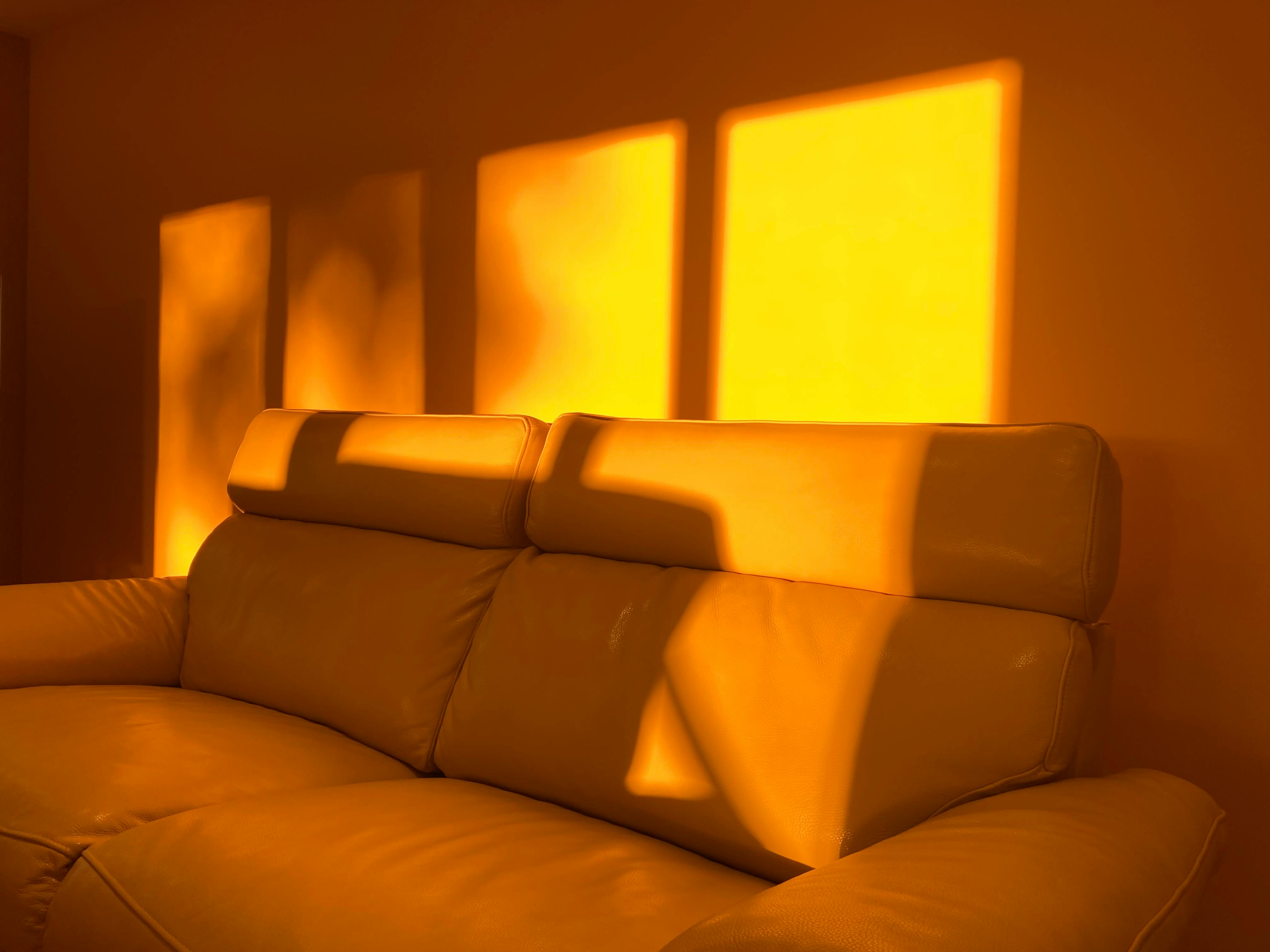 Warm golden sunlight casts cozy shadows over a leather sofa, creating a serene ambiance.