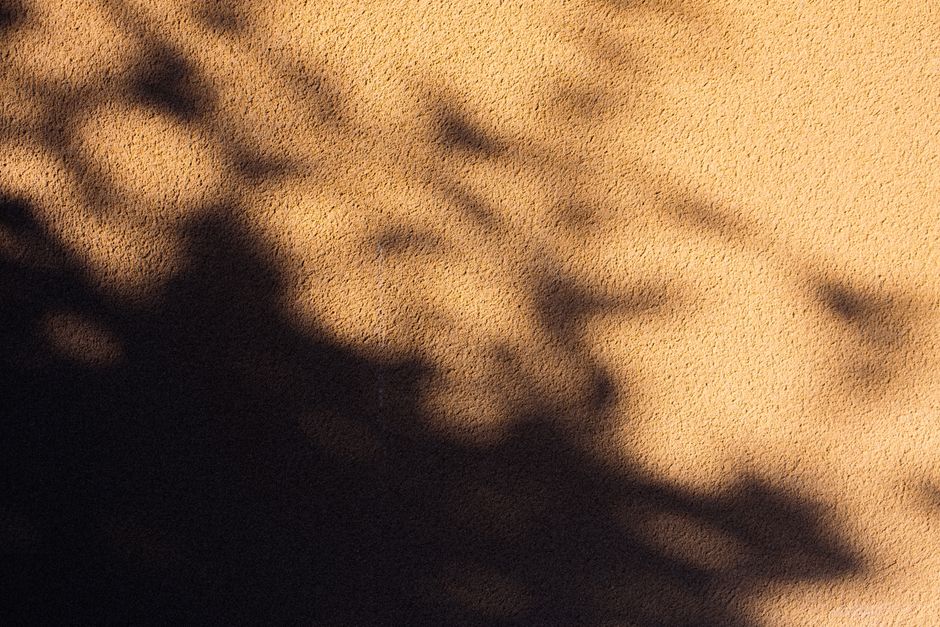 Textured wall with abstract shadows, creating a unique artistic pattern.