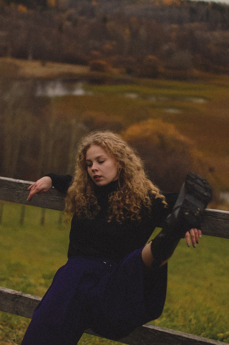 Pretty Woman Sitting On A Wooden Fence