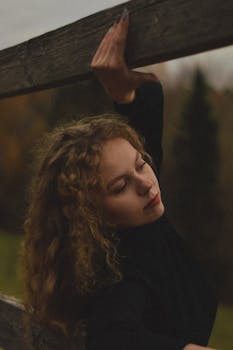 Woman with curly hair poses outdoors, showcasing calm and serenity.