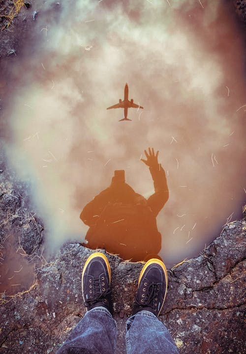Reflection of a Person and an Airplane on a Puddle