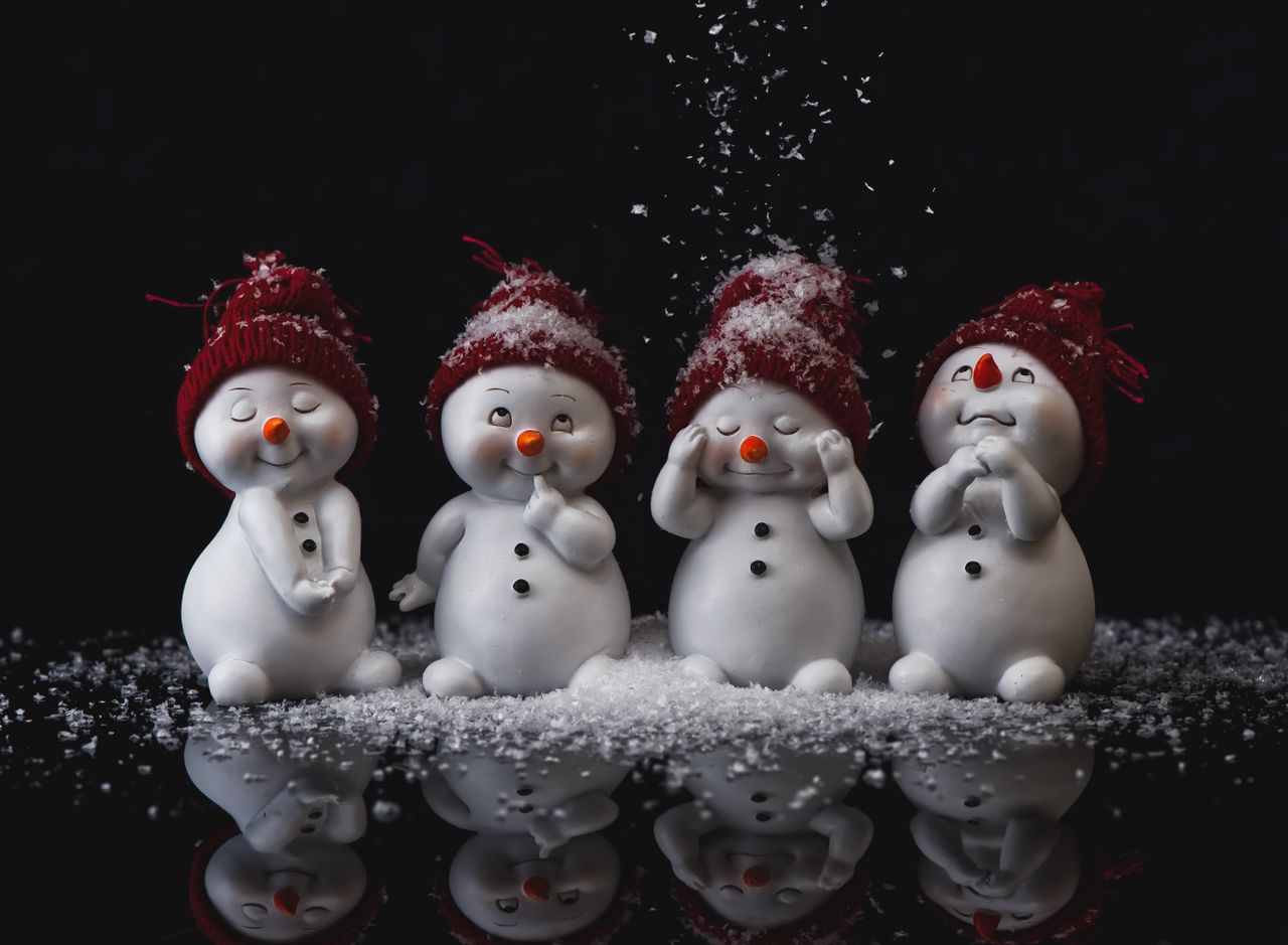 adorable snowman figurines with red hats amidst falling snow creating