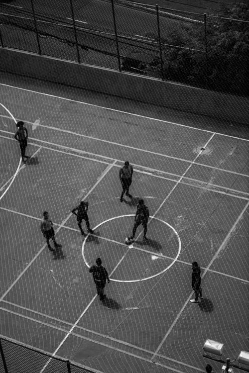 Free Aerial shot of people playing on a sports ground in a black and white setting. Stock Photo