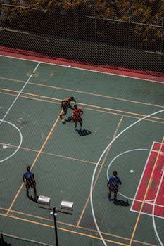 Aerial shot of four men playing basketball on an outdoor court.