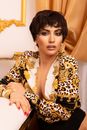 Woman Wearing a Animal Print Blouse Sitting Beside the Bed