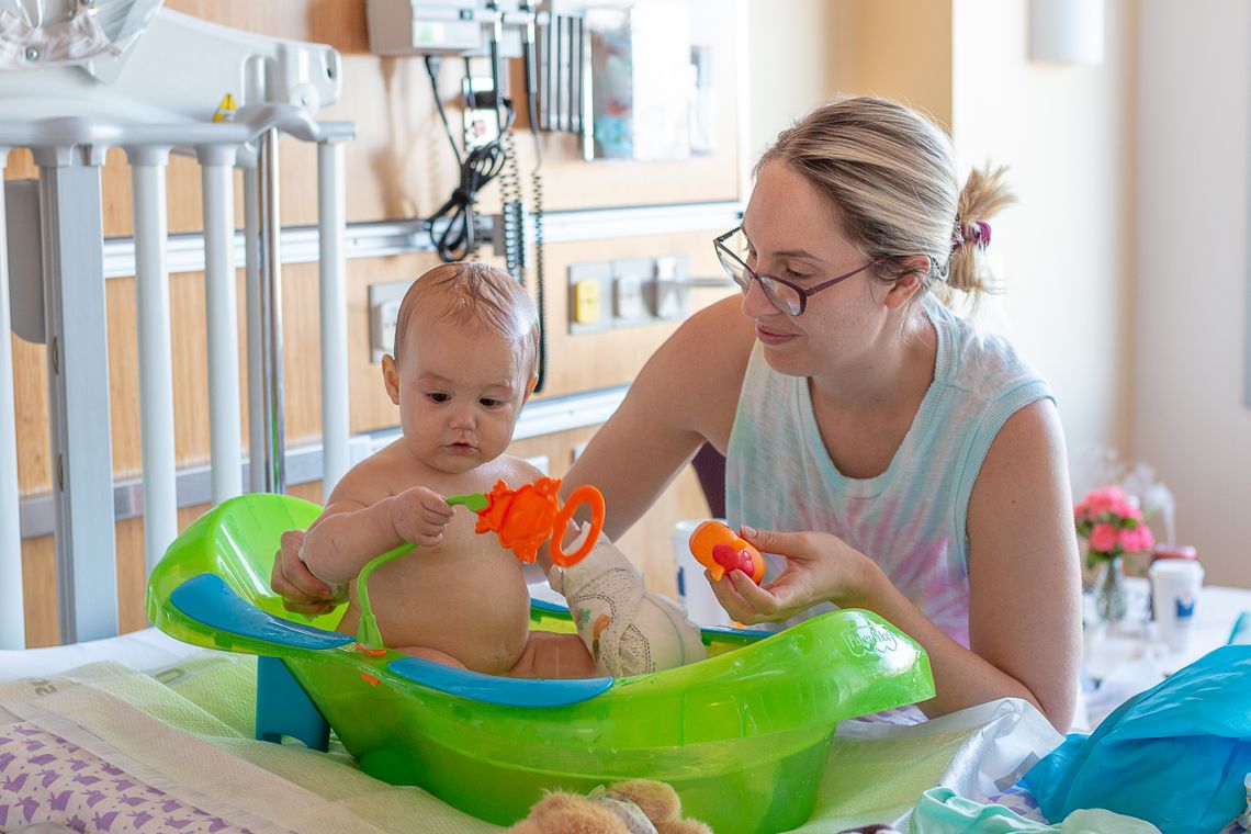 A mother gently bathing her baby