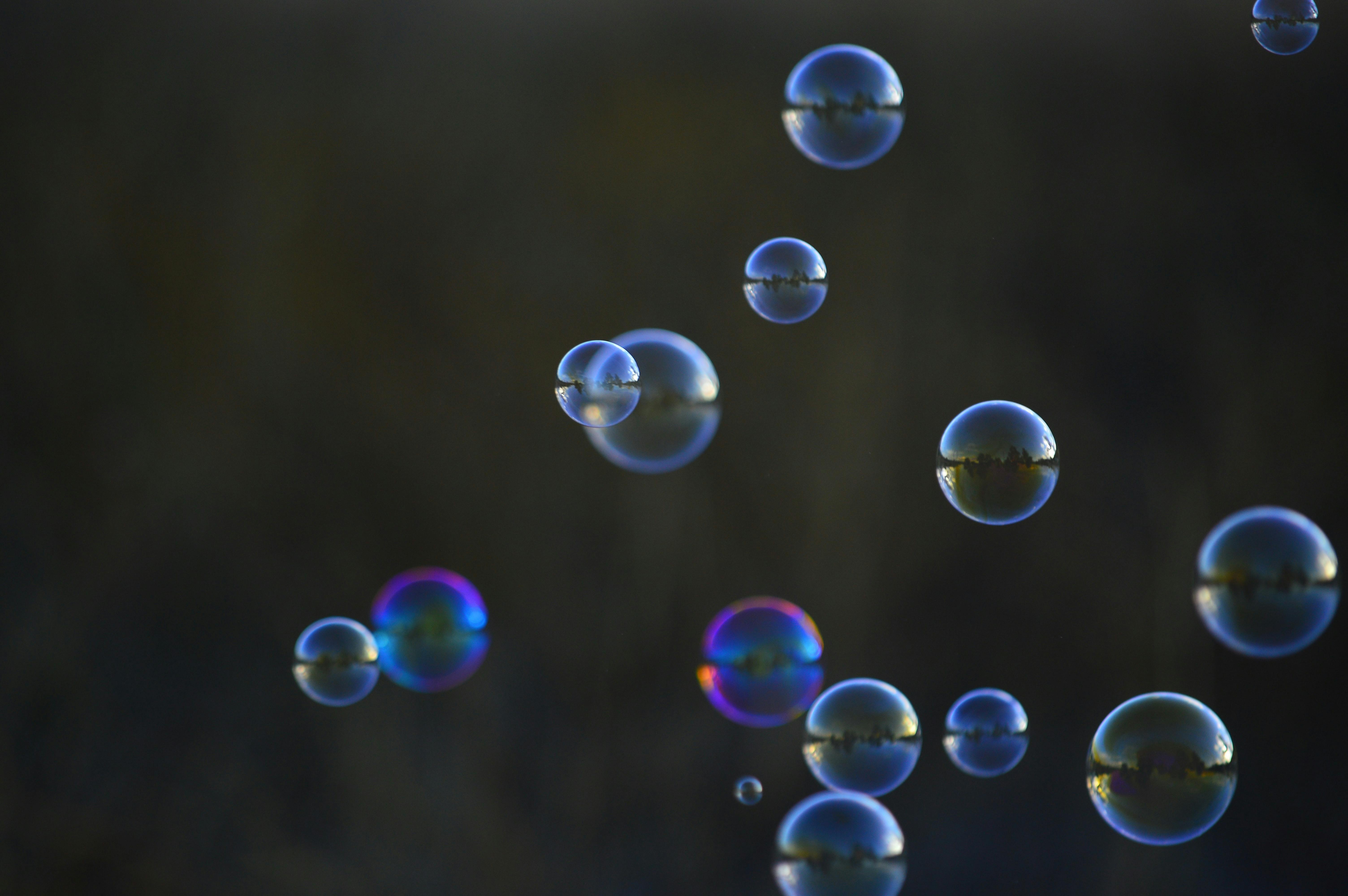 Captivating close-up of floating soap bubbles on a blurred dark background, showcasing vibrant reflections.