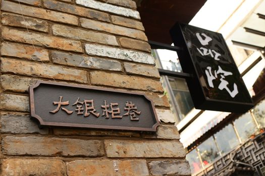 Close-up of a brick wall with traditional Chinese signs in a city environment.